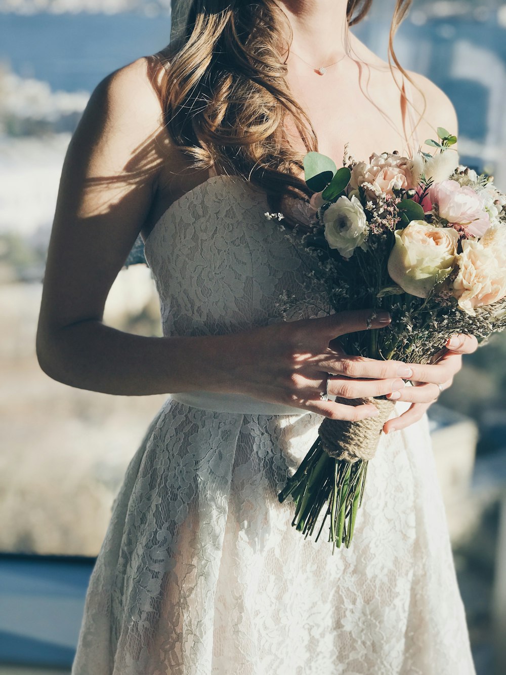 꽃을 들고 흰색 꽃무늬 끈이 없는 드레스를 입은 여자