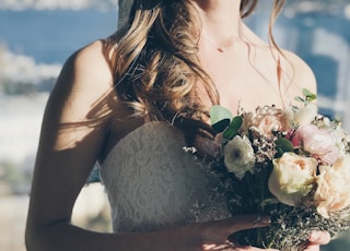 woman in white floral strapless dress holding flowers