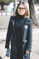 woman wearing sunglasses holding black Android smartphone