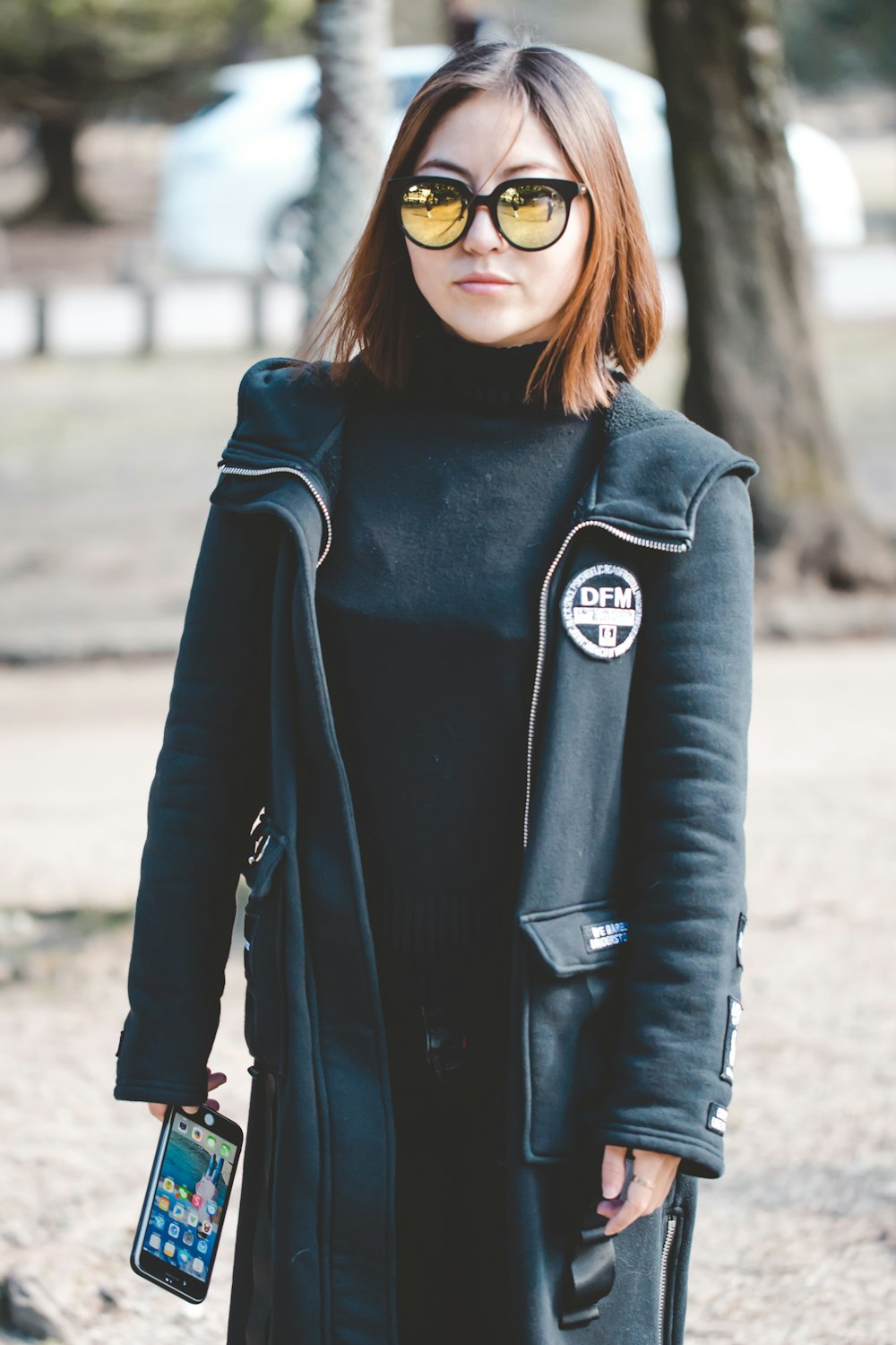 woman wearing sunglasses holding black Android smartphone