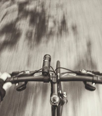 Close-up of a cyclist's hands gripping the handlebars with a blurred background of pilgrims.
