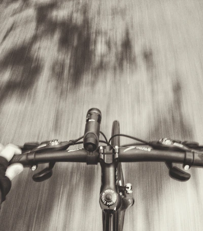 Close-up of a cyclist's hands gripping the handlebars with a blurred background of pilgrims.