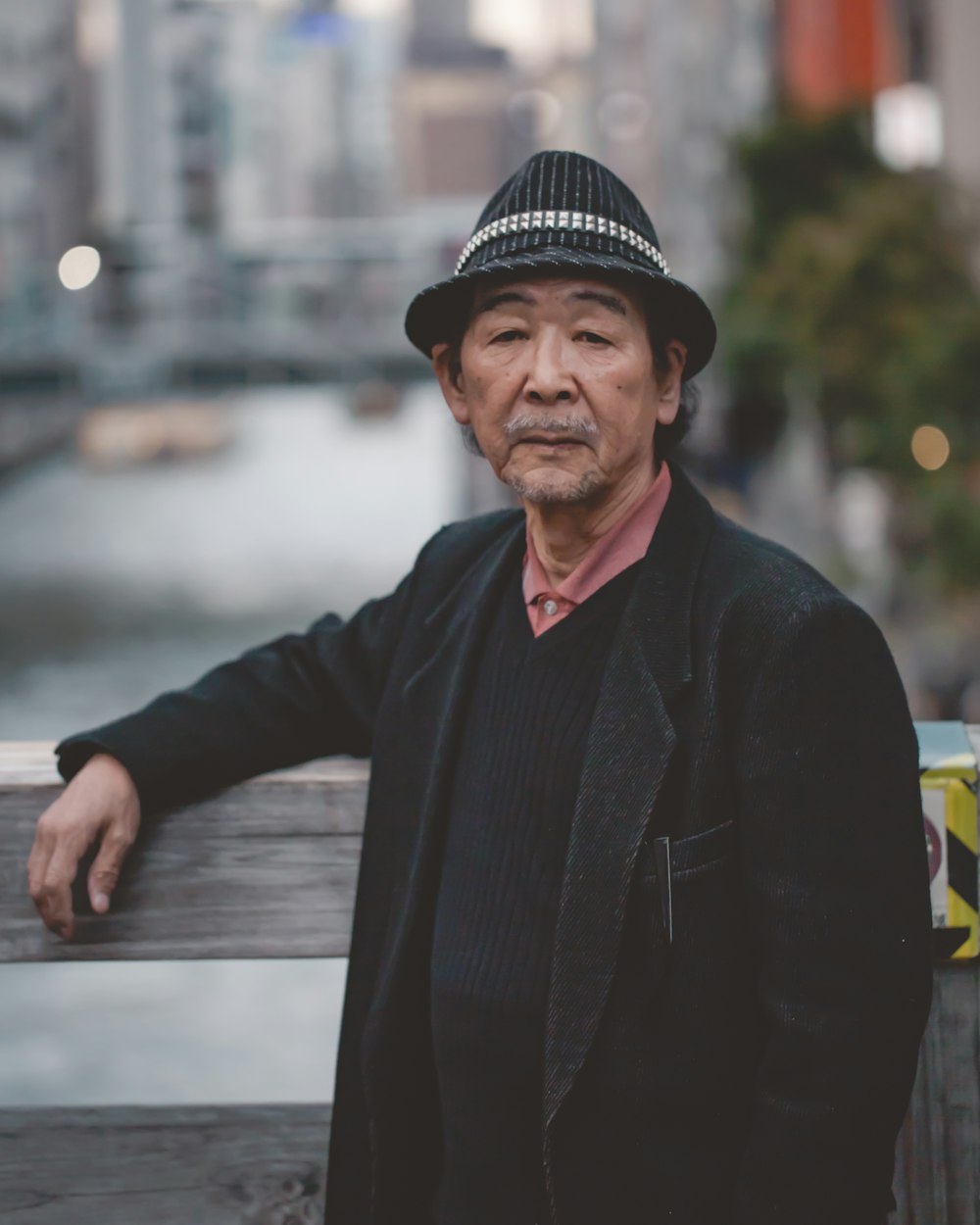 man wearing black hat standing against wooden handrail