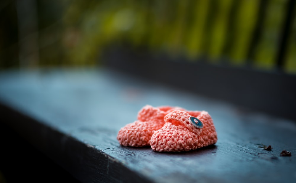 Paar rosafarbene Strickschuhe für Babys auf der Bank