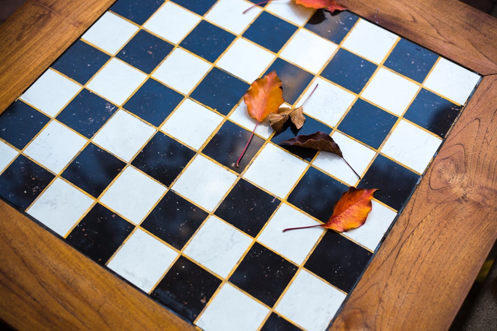 blue and white marble top, brown wooden framed chessboard containing dried leaves