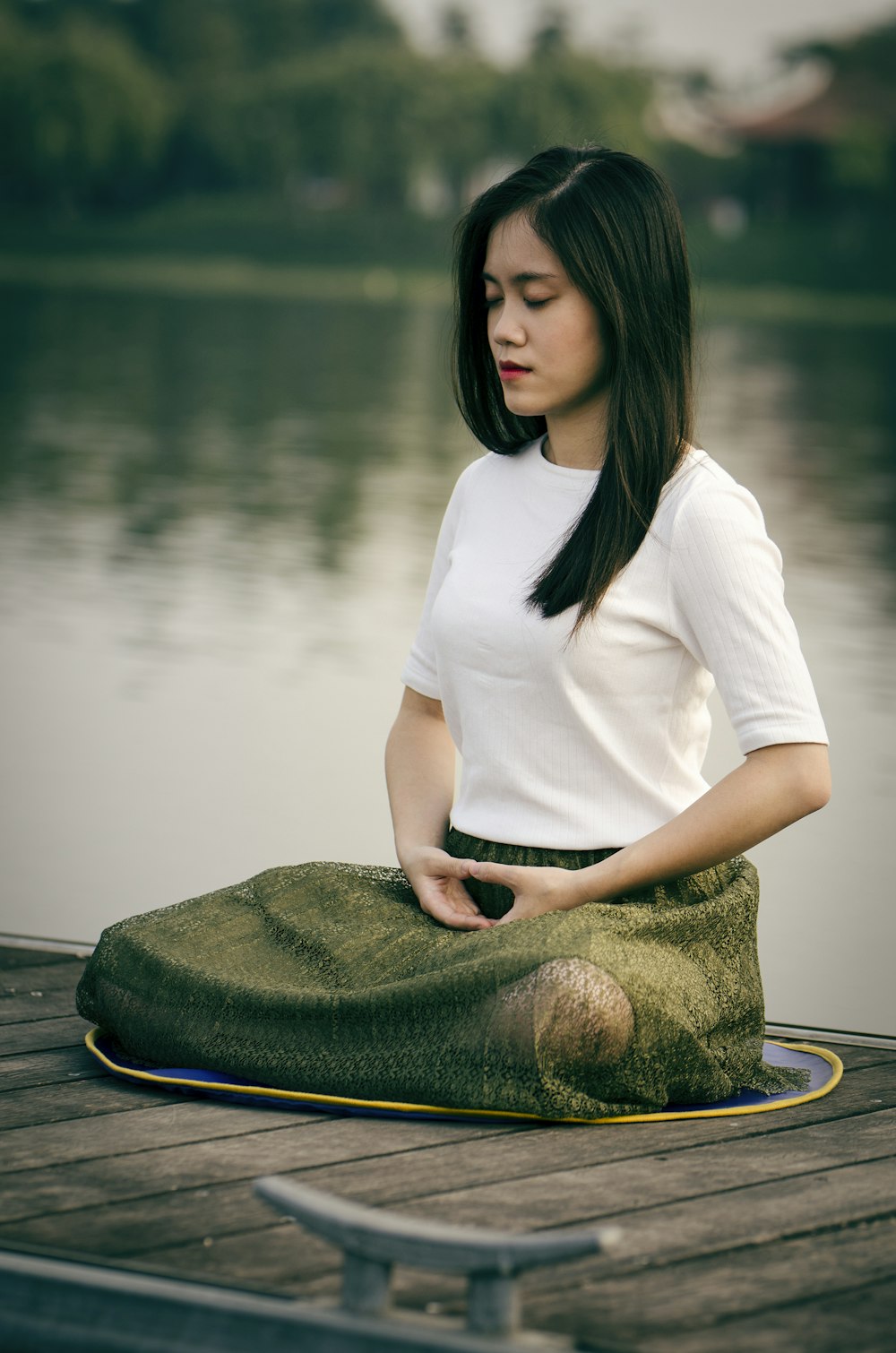 Frau meditiert tagsüber auf Holzsteg