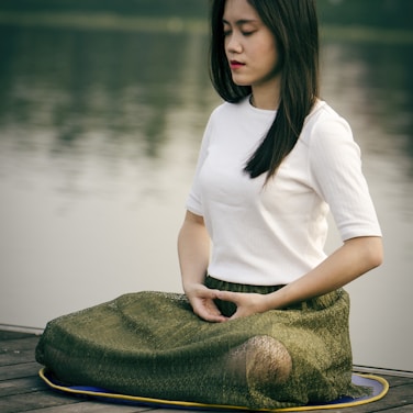 woman meditating on wooden dock during daytime