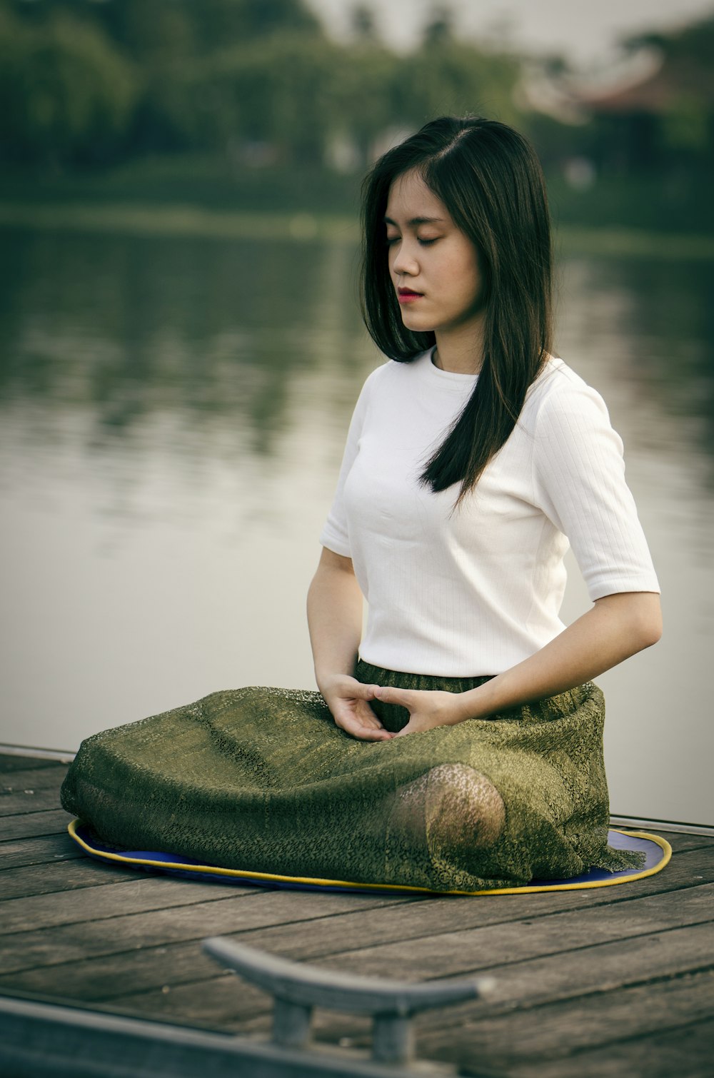 woman meditating on wooden dock during daytime