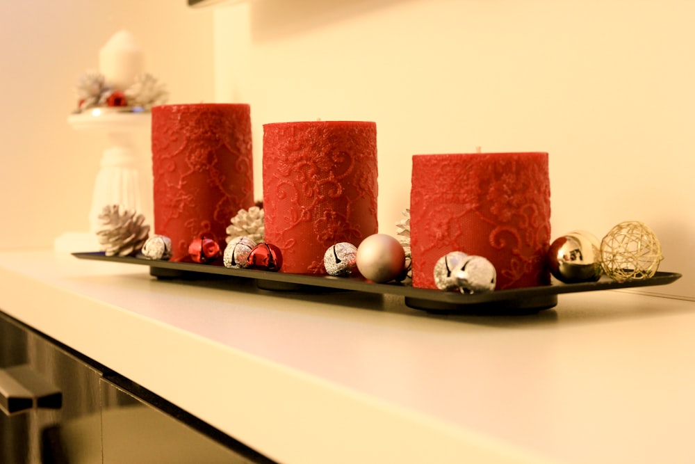 three red pillar candles on black holder