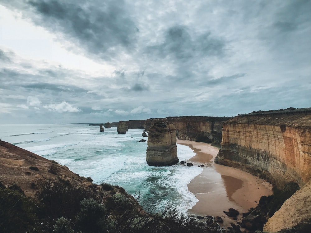 cliff beside sea under gray sky