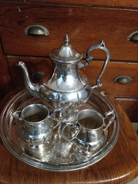 A professional appraiser carefully examining a vintage silver tea set in a well-lit room.
