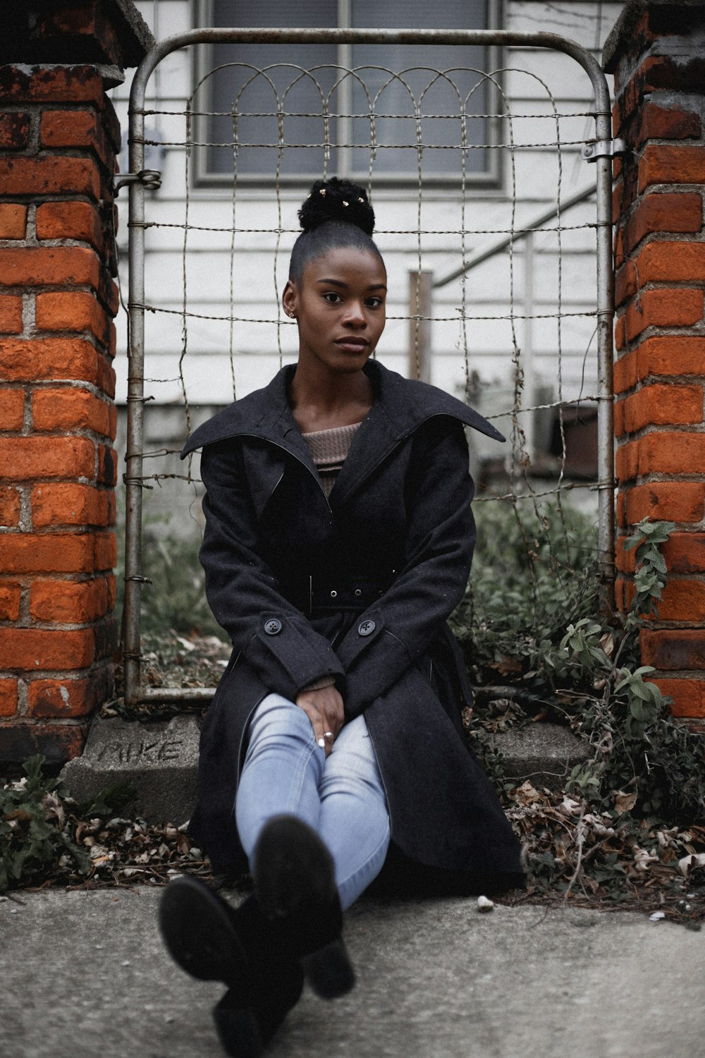 woman sitting near grey gate