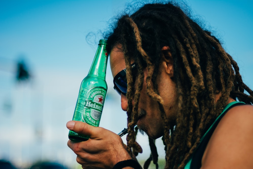 persona sosteniendo una botella de cerveza Heineken