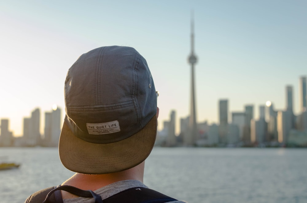 Persona con sombrero gris mirando hacia la ciudad durante la fotografía diurna