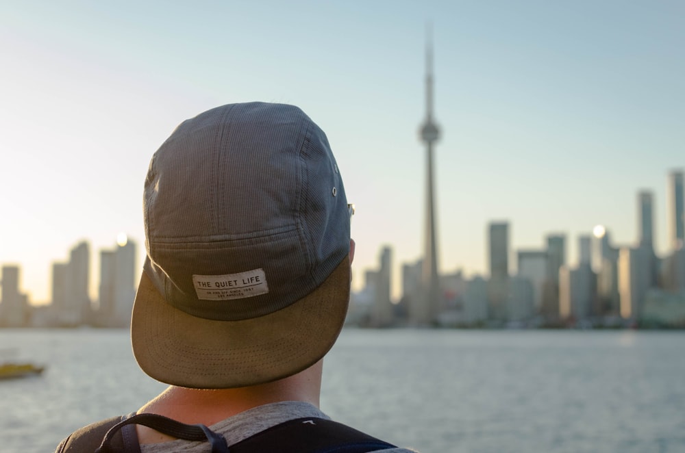 person wearing gray hat facing on city during daytime photography