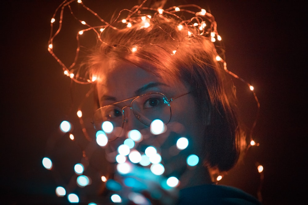 woman wearing brown framed eyeglasses with string lights on her head