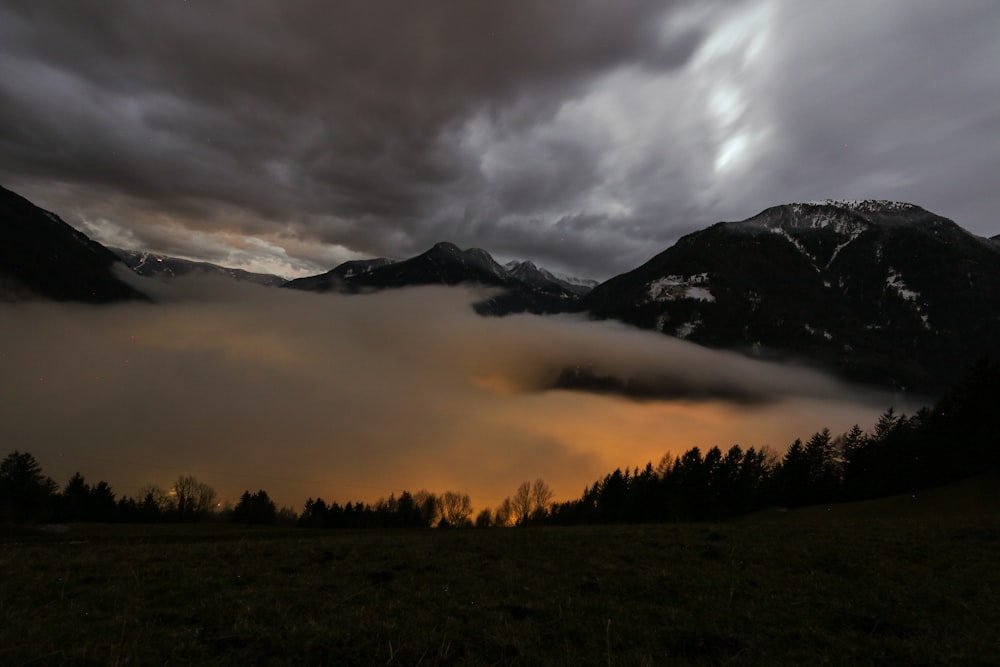 landscape photo of mountain surrounded by clouds under cloudysky