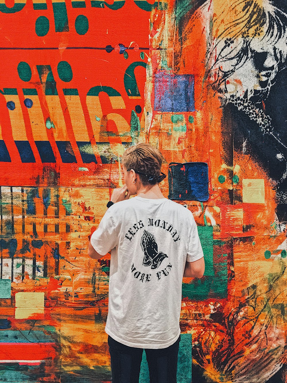uomo che tiene il mento di fronte a un muro dipinto multicolore