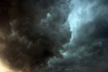 Dark, swirling storm clouds dominate the sky, creating a dramatic and intense atmosphere. The clouds are dense and textured, with areas of lighter and darker shades, suggesting impending heavy rain or a thunderstorm.