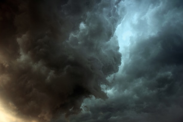 Dark, swirling storm clouds dominate the sky, creating a dramatic and intense atmosphere. The clouds are dense and textured, with areas of lighter and darker shades, suggesting impending heavy rain or a thunderstorm.