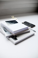 Stack of ultra-minimal kagei exec notebooks arranged neatly with a black pen.