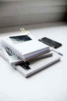 A stack of spiral notebooks with vibrant covers resting beside a pen and coffee cup.