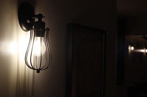 A matte black wall sconce illuminating a hallway with a soft, dimmable LED light.