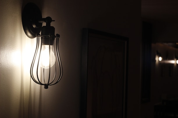 Close-up of a beautifully crafted wall sconce glowing softly in an upscale hotel hallway.