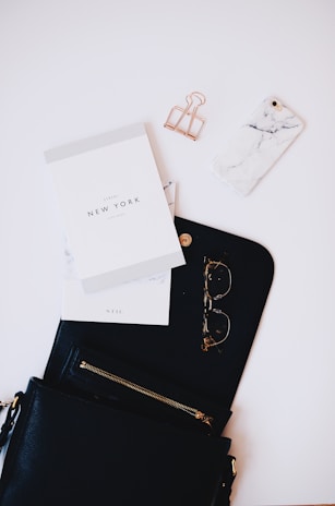 gold framed sunglasses, black phone case near gold clip