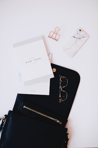 gold framed sunglasses, black phone case near gold clip