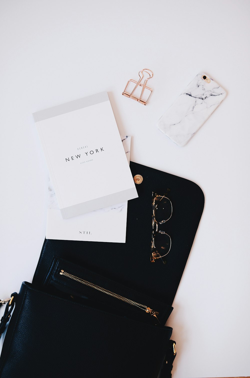 gold framed sunglasses, black phone case near gold clip