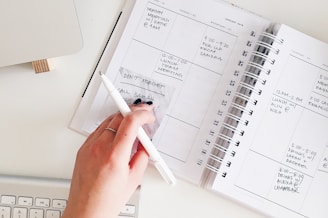 person holding notepad and pen flat lay photography