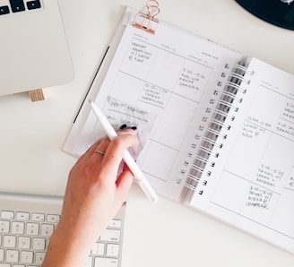 person holding notepad and pen flat lay photography