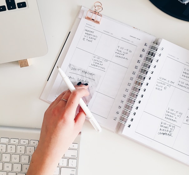 person holding notepad and pen flat lay photography