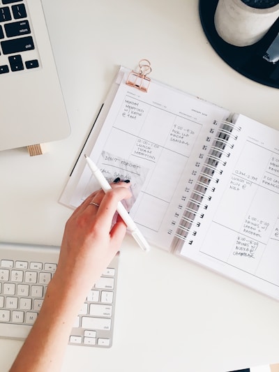 A close-up of a hand writing on a daily schedule planner with a pen.