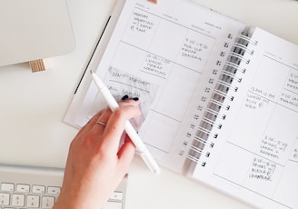 person holding notepad and pen flat lay photography