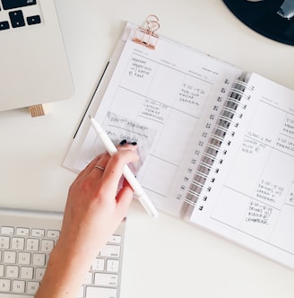 person holding notepad and pen flat lay photography