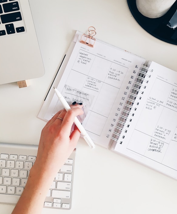 person holding notepad and pen flat lay photography