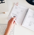 person holding notepad and pen flat lay photography