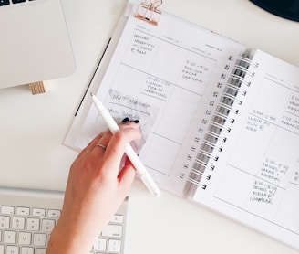 person holding notepad and pen flat lay photography