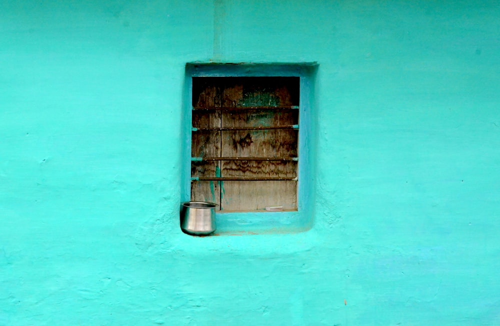 grauer Stahlbehälter am Fenster mit blaugrüner Farbe