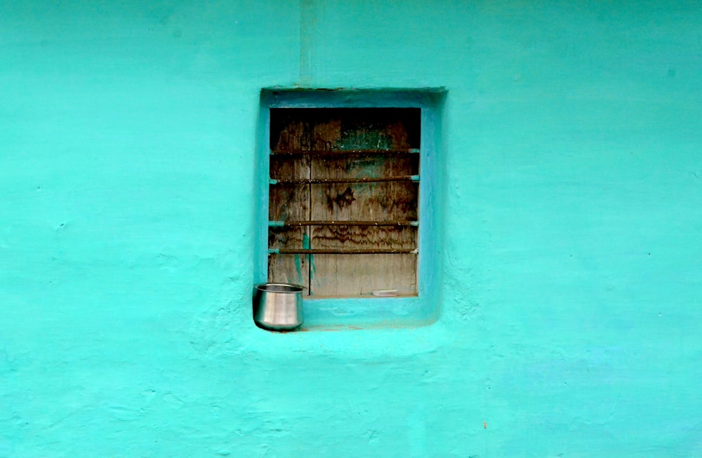 recipiente de aço cinza na janela com tinta teal