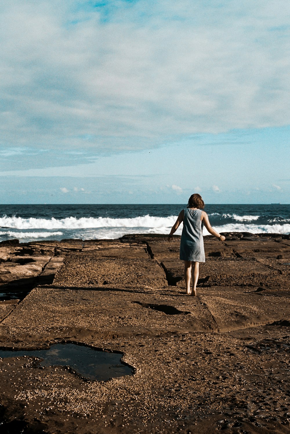 a woman walking on top of black rock formation