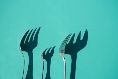 three gray metal forks casting shadow on green surface contemporary zoom background