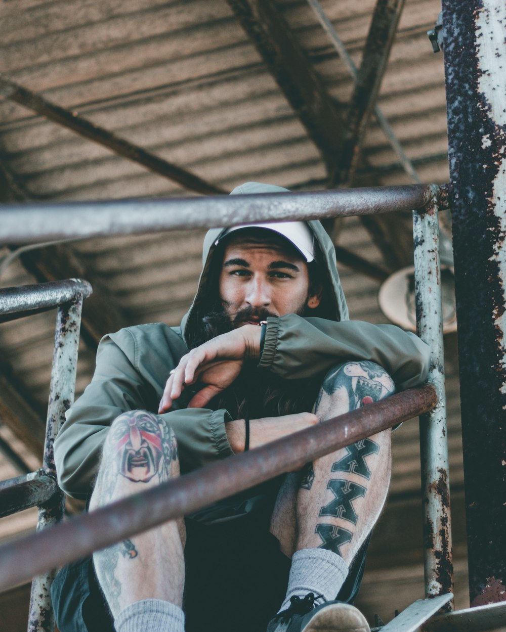 man sitting on stairway wearing green hooded jacket