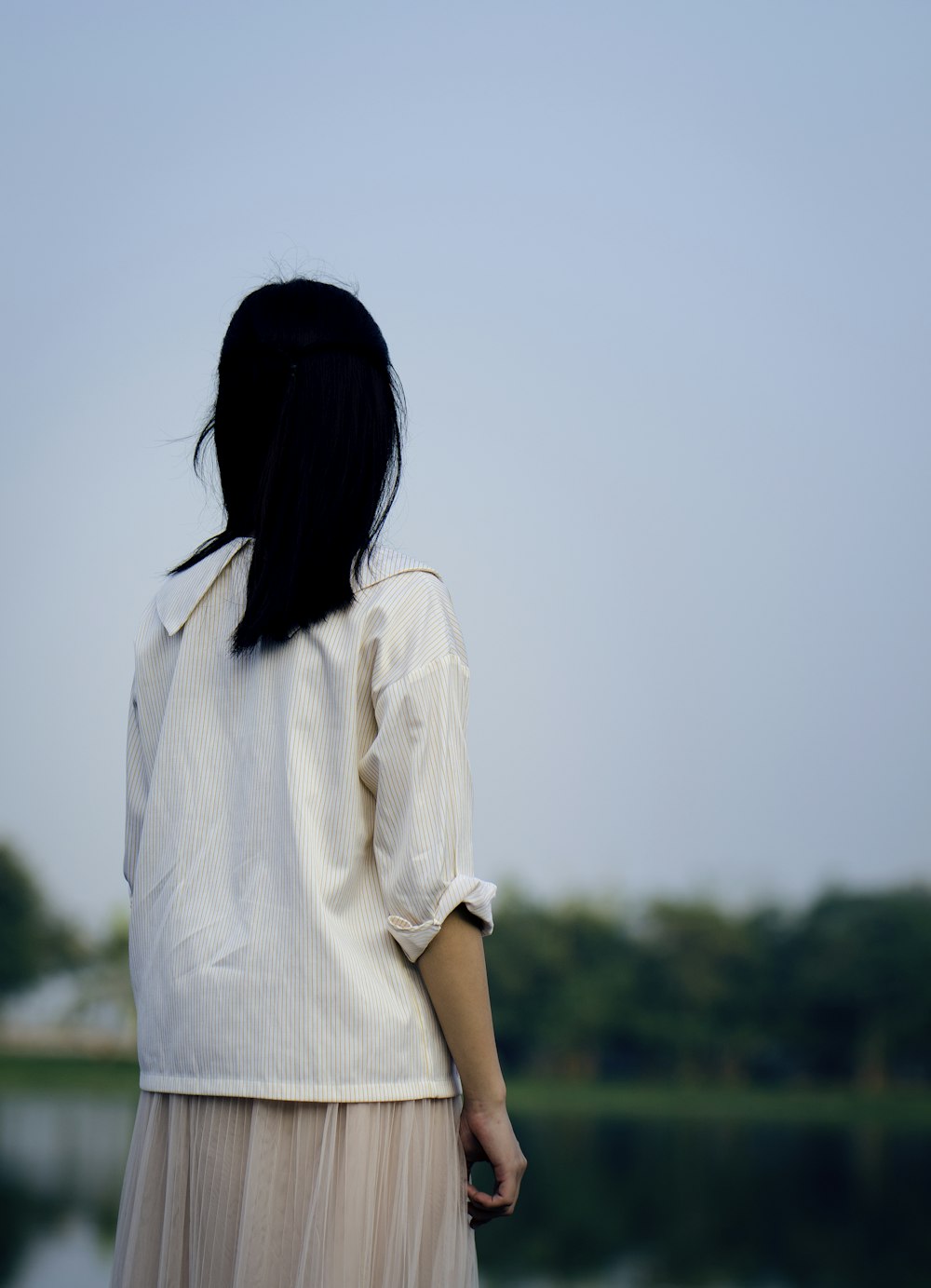 femme portant une chemise blanche debout sous le ciel bleu pendant la photographie de jour