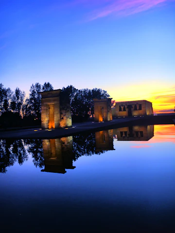 A panoramic view of towering megalithic structures silhouetted against a golden sunset.