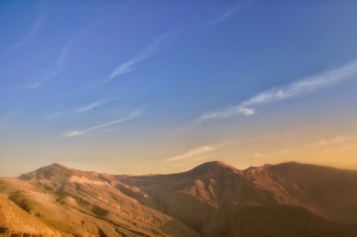 A serene panoramic view of Syrian mountains under a clear blue sky with a golden sunrise.