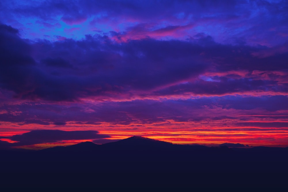 silhouette di montagna sotto il cielo nuvoloso durante l'ora d'oro