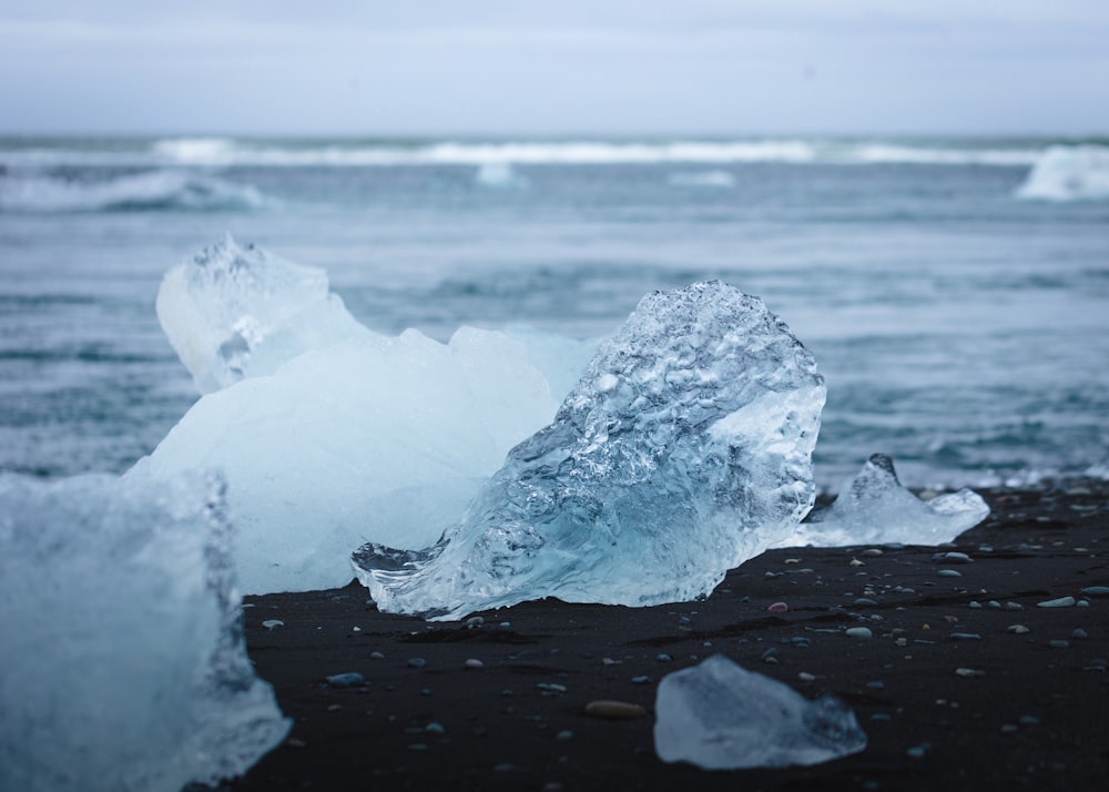 clear ice fragment on black stone during daytime